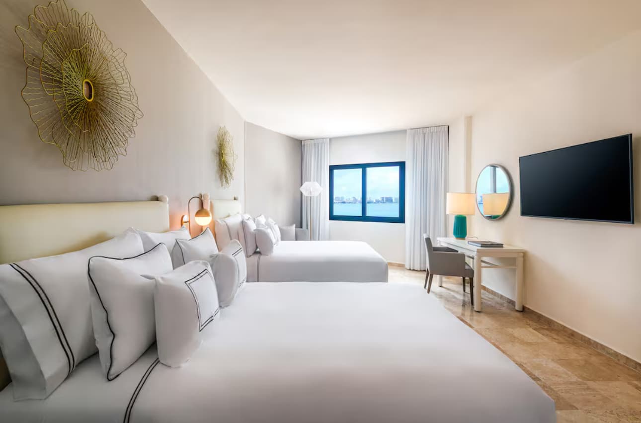 Habitación terminada — camas twin con cabeceras retapizadas, vista al océano