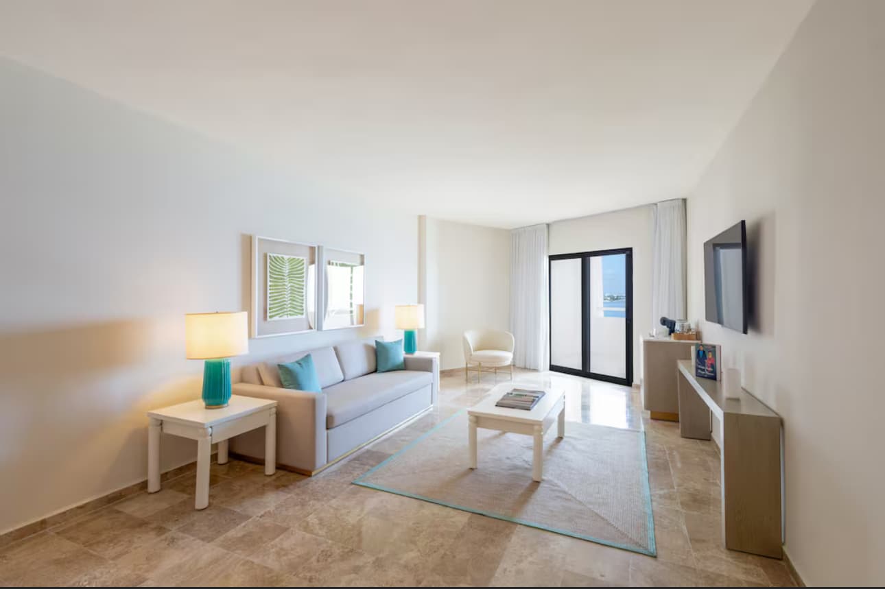 Sala de suite — sofá, mesa de centro, lámparas en turquesa, vista a la laguna