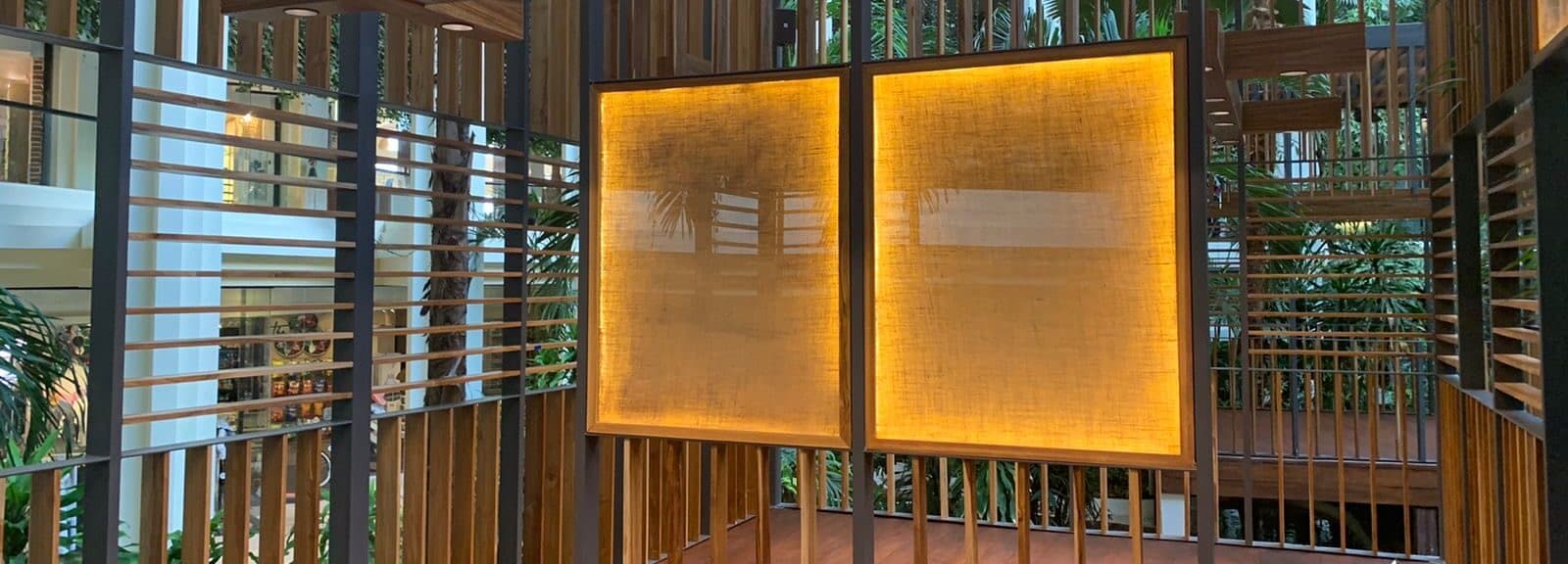 Paneles tejidos ámbar retroiluminados enmarcados en tablillas de madera oscura — detalle de ebanistería arquitectónica