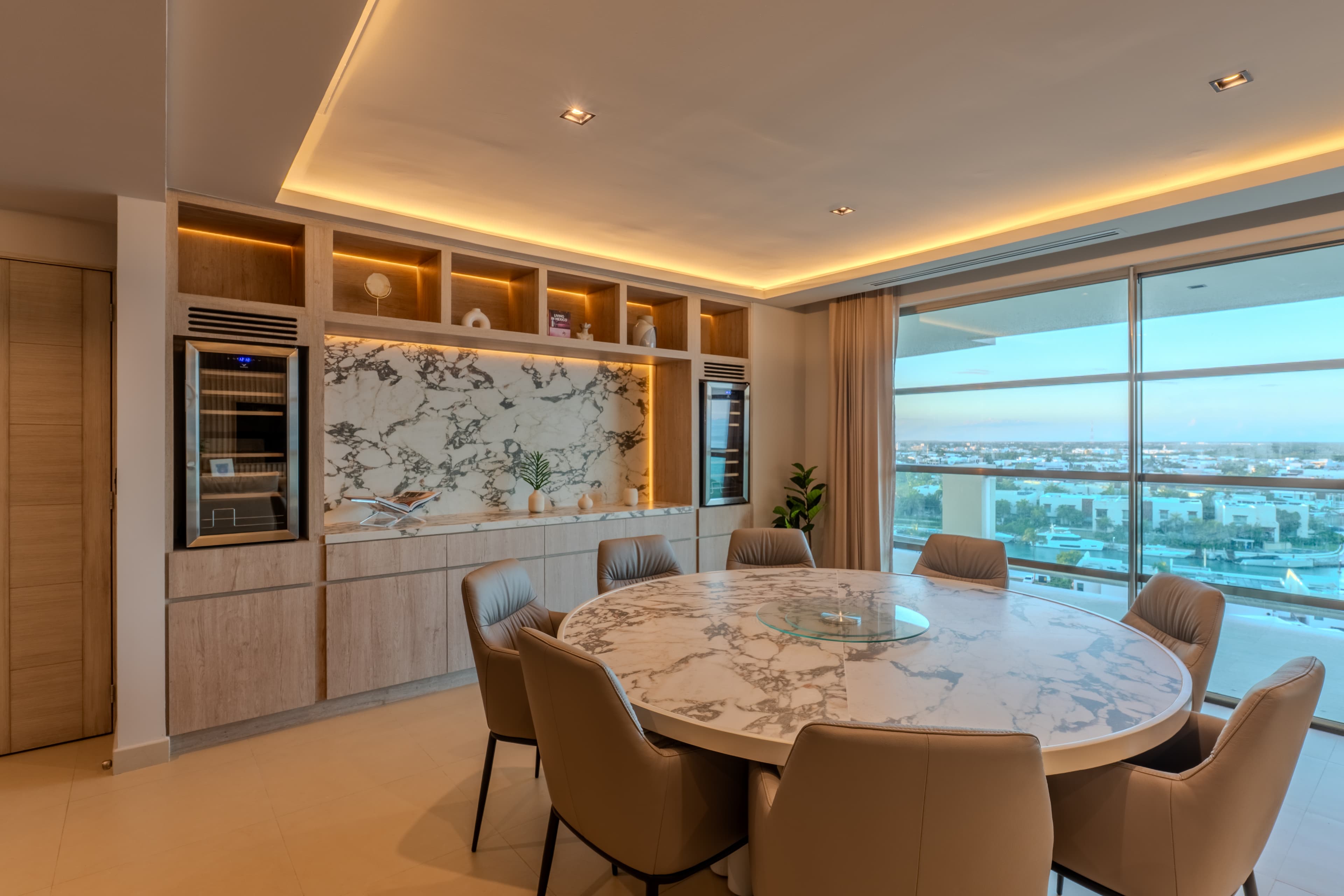 Apus 904 — comedor con muro de ebanistería a medida y vistas a la ciudad al atardecer, Cancún