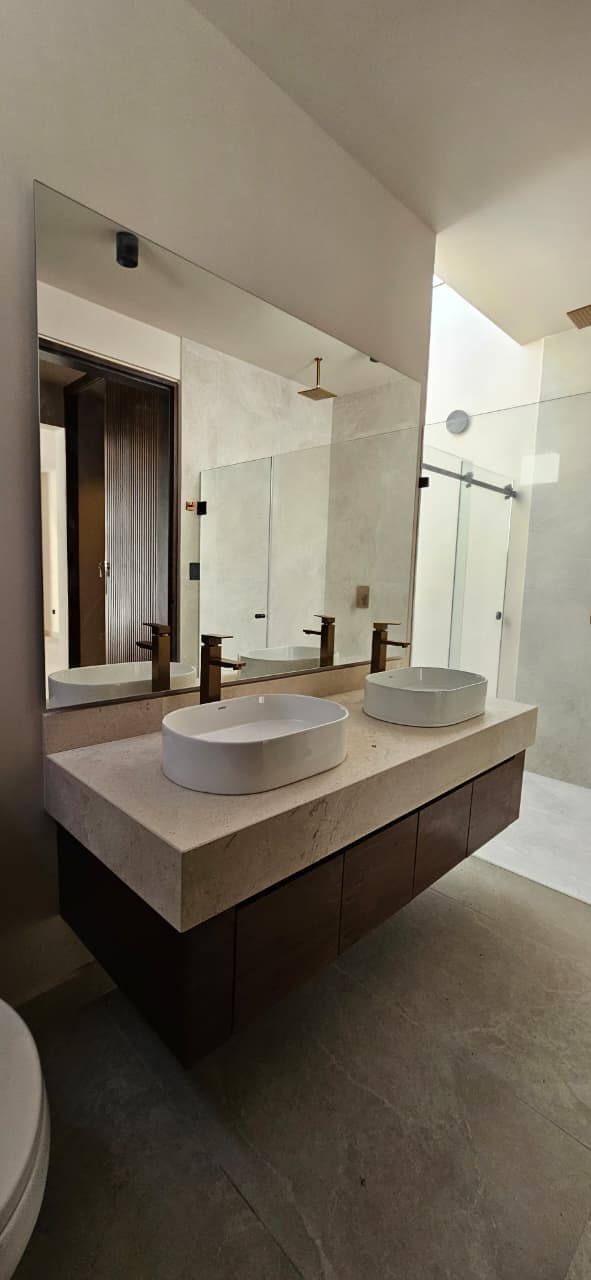 Casa Juuba — vanidad flotante del baño principal con cubierta de travertino