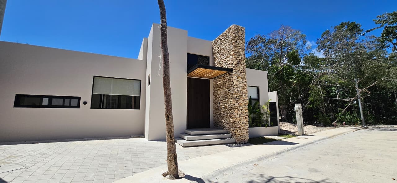 Casa Juuba — detalle de acceso, columna de piedra y puerta pivotante de madera